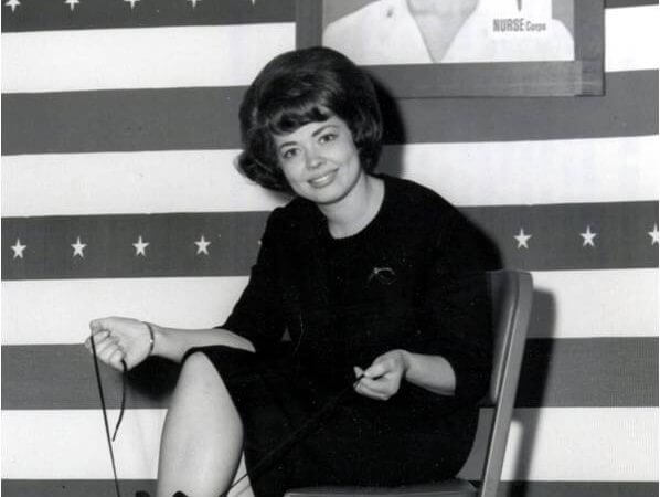 Karren Kowalski sits in a chair and laces up a pair of Army boots